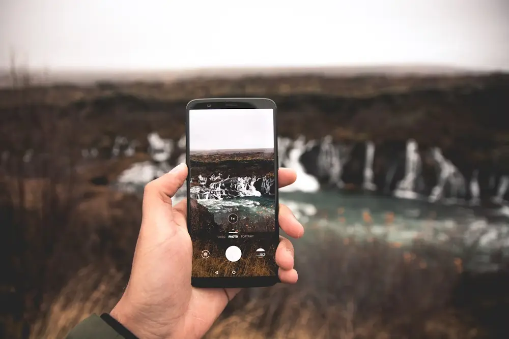 A person using a black smartphone taking a photo