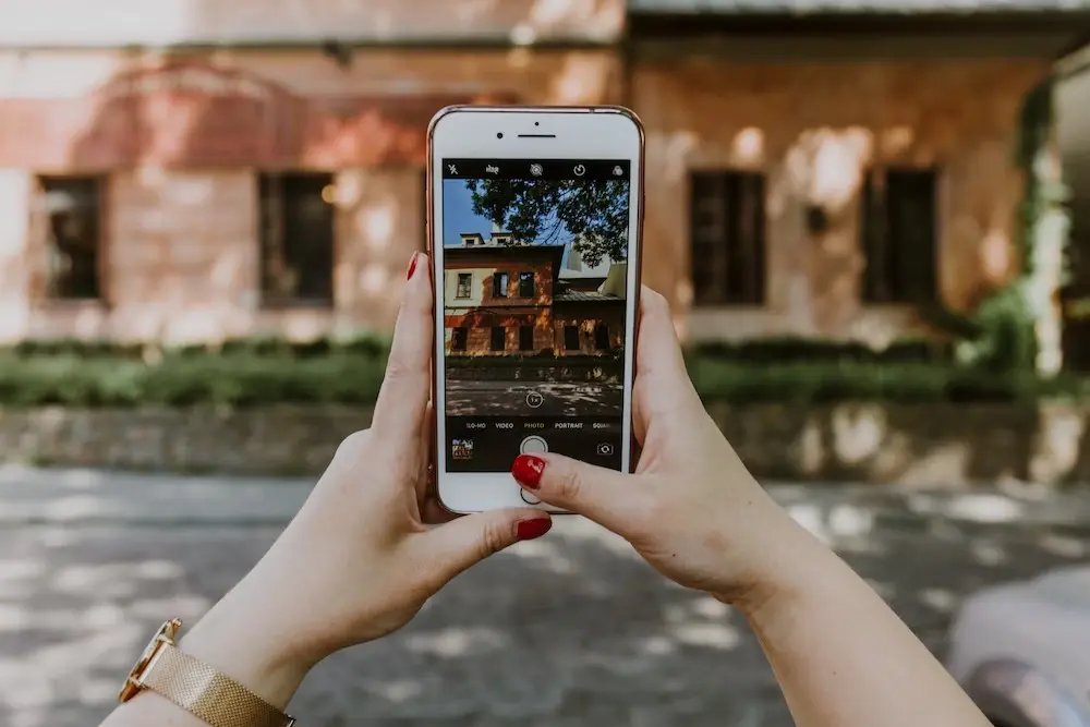 Woman taking a photo of brown house