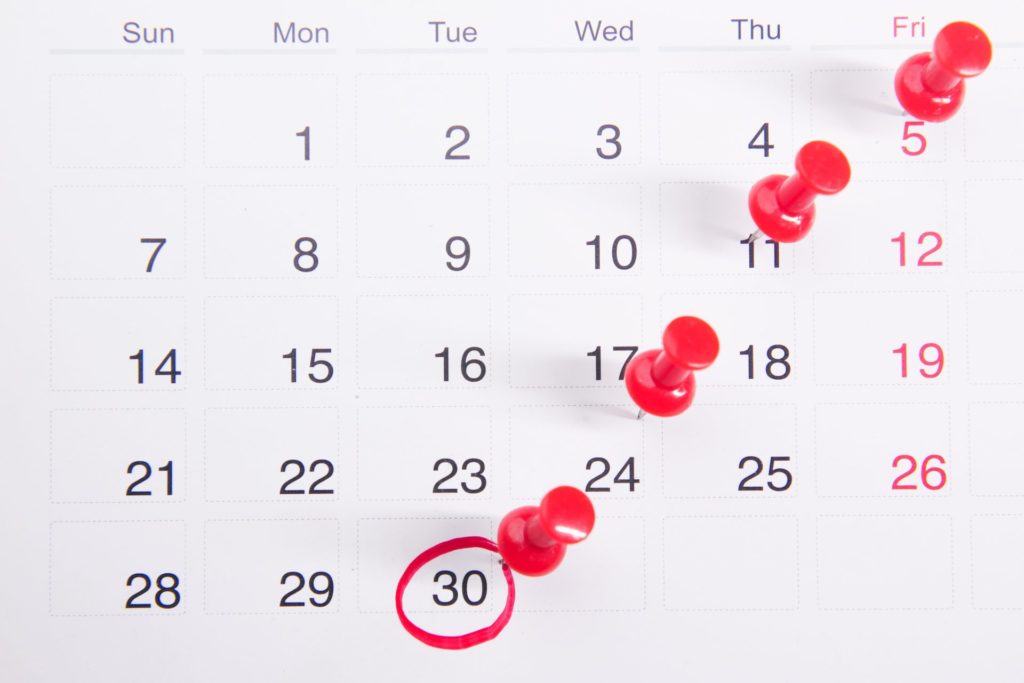A calendar page with dates marked with red push pins